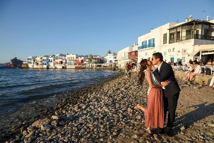 Couple kissing on the pebble shore at Little Venice at sunset during a Mykonos photoshoot