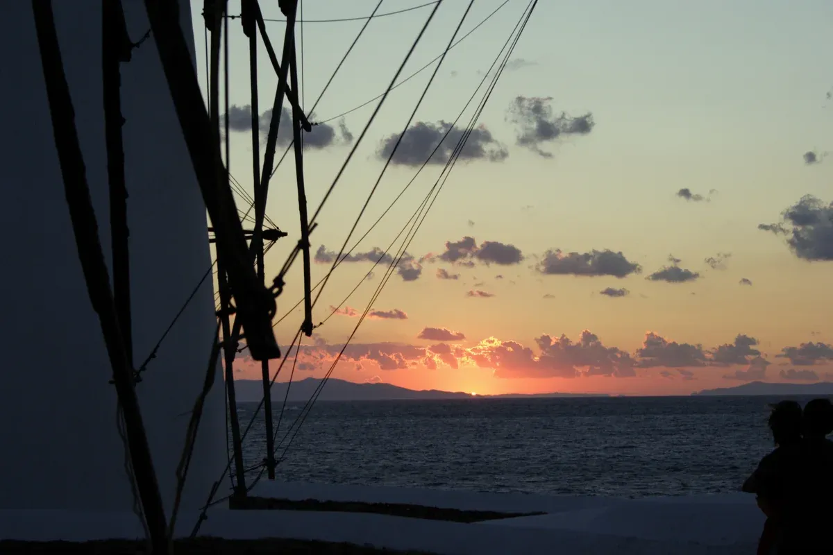 Sun setting behind Syros seen from the lower windmills, the golden-hour light a Mykonos photoshoot is timed for